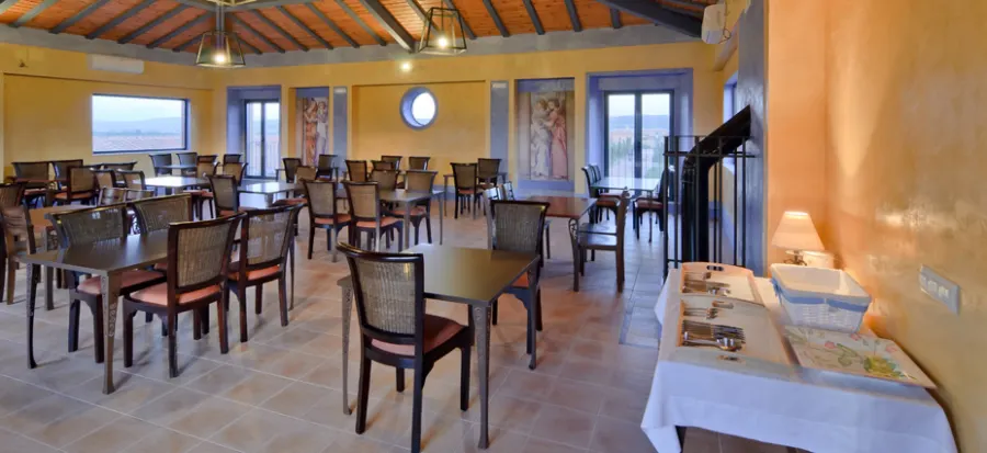 Salón con mesas montadas y ventanales al valle